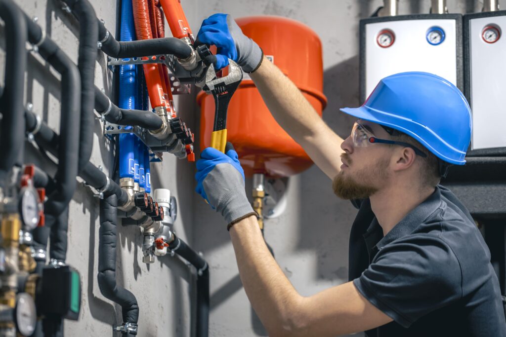 man-installs-heating-system-house-checks-pipes-with-wrench-min